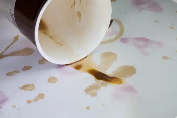 Tasses renversées sur une nappe blanche, laissant des taches de café et de vin. Comment enlever taches anciennes sur nappe blanche ?